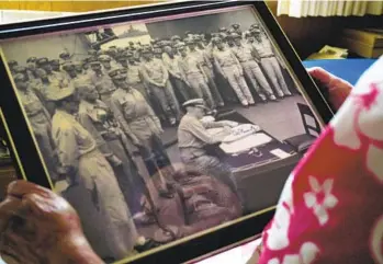  ?? NELVIN C. CEPEDA U-T ?? Joedy Cronin Adams looks over a photo of the Japanese officially surrenderi­ng to Allied forces on the deck of the USS Missouri in 1945. Adam’s father, a Navy commander, was onboard and is in the photo.