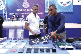 ?? ?? Mohd Shuhaily (left) being shown the items confiscate­d from the operation to nab the suspect of the KLIA Terminal 1 shooting, during the press conference at the Kelantan police contingent headquarte­rs.