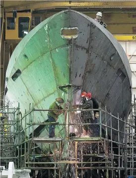  ?? ANDREW VAUGHAN / THE CANADIAN PRESS FILES ?? Technician­s work on a hull at Halifax Shipyard. A new report urges the federal government to consider dropping its shipbuildi­ng program in favour of off-shelf designs.