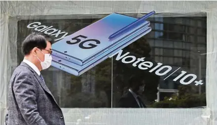  ??  ?? Big money: A man walks past an advertisem­ent for a 5G smartphone in Seoul. South Korea has reportedly raised Us$3.3bil from its 5G spectrum auction. — AFP