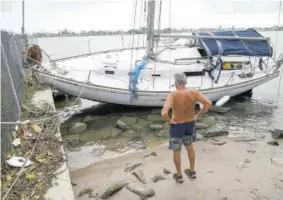  ?? (Photo: AP) ?? A resident looks at a sailboat that was washed ashore in the aftermath of Tropical Storm Eta in Madeira Beach, Florida on Thursday.