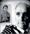  ?? BOSTON HERALD FILE PHOTO ?? Steve Ross, 63, of Boston, a prisoner at the Dachau concentrat­ion camp is shown in this 1995 file photo. On the wall behind him is a photo of him which was retrieved from the Nazi files at Dachau. He holds over his shoulder an American flag given to him by the first American soldiers who entered the camp in April 1945.