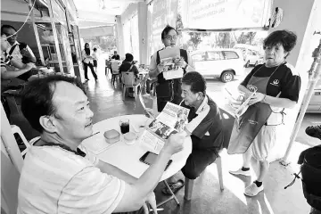  ??  ?? State Health Department officers distributi­ng rabies prevention flyers to the public at Sungai Maong Wet Market. — Photo by Muhammad Rais Sanusi