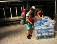  ?? AP/FRANCISCO SECO ?? Rail passengers take free bottled water Friday at a Brussels station before getting on a train bound for Amsterdam that had been delayed.