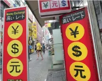  ?? — AP ?? People walk by signs of foreign currency outside a money exchange office at a shopping district in Seoul.