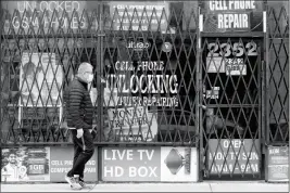  ?? ASSOCIATED PRESS ?? A MAN WALKS BY A closed store during the COVID-19 in Chicago on April 30.