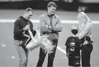  ??  ?? New Orleans quarterbac­k Drew Brees, left, plays with his children as Tampa Bay quarterbac­k Tom Brady speaks with Brittany Brees after the Buccaneers beat the Saints 30-20 in the NFL playoffs on Sunday in what might have been the final game of Brees' career. [AP PHOTO/BUTCH DILL]