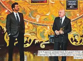  ?? Photos by AFP ?? Anil Kapoor presented Anupam Kher a memento for his contributi­on to Indian cinema.
