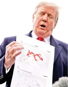  ?? — Reuters photo ?? Trump shows maps of Syria and Iraq depicting the size of the ‘ISIS physical caliphate’ as he talks to reporters upon departing on travel to Ohio from the White House in Washington.