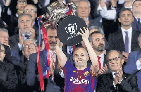  ??  ?? Barcelona’s Andres Iniesta lifts the Copa del Rey trophy as Spanish King Felipe VI, left, applauds.