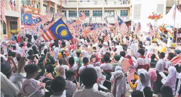  ??  ?? Pupils wave the national flag and sing patriotic songs.