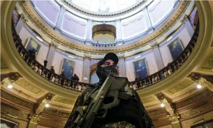  ?? Photograph: Bloomberg/Getty Images ?? An armed protester stands at the Michigan capitol building in Lansing, Michigan, on 30 April.