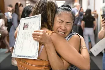  ?? ASHLEE REZIN/SUN-TIMES ?? Ofelia Peregrino, who was born in Mexico, holds her naturaliza­tion certificat­e and cries after taking the oath of American citizenshi­p on Tuesday at the Dirksen Federal Building.