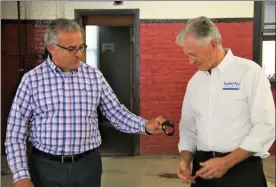  ?? Danielle ray / sentinel & enterprise ?? leominster mayor dean mazzarella, left, hands back a safetynet tracking system watch to safetynet Vice president of operations ralph poland on Wednesday at the leominster Fire department.