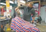  ??  ?? Mike Brown (right) a barber and health advocate, gives Vyron Cox Jr. a cut in Hyattsvill­e, Md. Brown is a member of a program that helps barbers and hair stylists get certified to talk to community members about health.