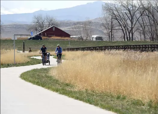  ?? JENNY SPARKS
Loveland Reporter-herald ?? Jan Wideman, right, rides her bike with Steve Wideman, pulling Nathan Wideman, at Sunset Vista Natural Area in Loveland on Tuesday.