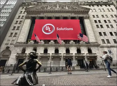  ?? (AP/Peter Morgan) ?? People pass the Fearless Girl statue outside of the New New York Stock Exchange on Friday in New York.