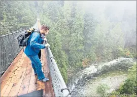  ?? TOURISM VANCOUVER ?? Visitors to the picturesqu­e Capilano Suspension Bridge Park check out the river 230 feet below the swaying, wobbly bridge.