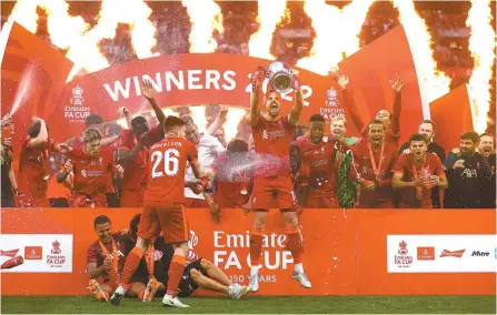  ?? Reuters-Yonhap ?? Liverpool’s Jordan Henderson, center, lifts the trophy as they celebrate after winning the FA Cup against Chelsea at Wembley Stadium, London, Saturday.