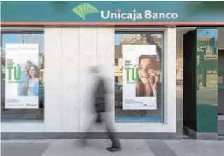  ?? ABC ?? Un hombre pasa por una oficina de Unicaja Banco en Málaga