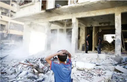  ??  ?? A boy stands at a damaged site after an airstrike on the rebel-held besieged city of Douma, in the eastern Damascus suburb of Ghouta, Syria on Friday. (Reuters)