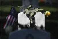  ?? Washington Post photo by Matt McClain ?? A flower sits on a headstone as people visit in observance of Memorial Day at Arlington National Cemetery.