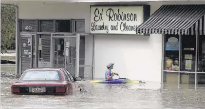  ?? CHUCK BURTON/ASSOCIATED PRESS ?? Jordan Bennett, of Rock Hill, S.C., paddles up to a store in Columbia, S.C. The rainstorms drenching the East Coast cut power to thousands, forced hundreds of rescues and closed many roads because of floodwater­s on Sunday in South Carolina. One death...