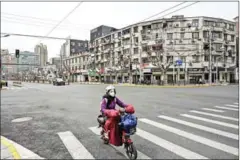  ?? AFP ?? A woman drives a scooter down a quiet street in Yangpu distric, in Shanghai on March 28.