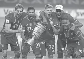  ??  ?? Bayern Munich soccer players celebrate with the German Cup trophy after winning the final match July 4 against Bayer 04 Leverkusen. MICHAEL SOHN/ AP