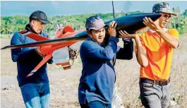  ?? — AFP ?? Workers carrying a miniature test rocket as Indonesia prepares for launch.