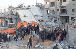  ?? HATEM ALI/AP ?? Palestinia­ns look at the destructio­n Friday after an Israeli strike on a residentia­l building in Rafah, Gaza Strip.