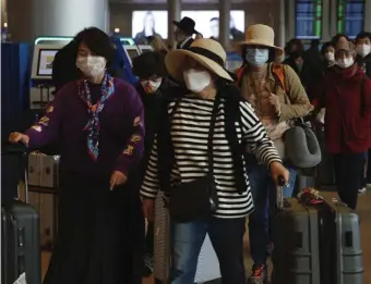  ?? AP ?? NO MASKING THEIR CONCERN: Tourists from Korea wear protective masks as they walk with their belongings at the Ben Gurion Airport near Tel Aviv, Israel, on Sunday.