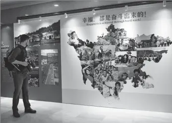  ?? AN YUAN / CHINA NEWS SERVICE ?? A journalist visits an exhibition showcasing the poverty alleviatio­n efforts in Chengdu, Sichuan province, on Wednesday. About 70 photos are on display.