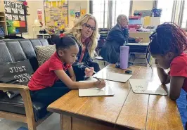  ?? EILEEN MCCLORY PHOTOS / STAFF ?? Teacher Julie Emmons works with two second-grade students on Wednesday at Madison Park Elementary.