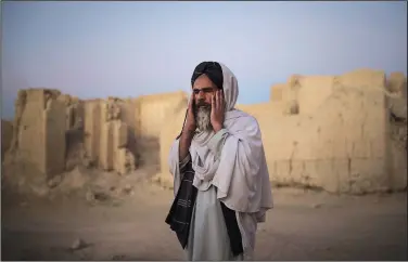  ?? ?? Mohammad Salim, the imam of Salar village, prays Oct. 12 outside a mosque at dusk in Salar.