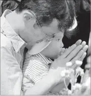 ?? TORU YAMANAKA / AGENCE FRANCE-PRESSE ?? A father helps his son pray for victims of the 1945 atomic bombing at the Peace Memoral Park in Hiroshima.