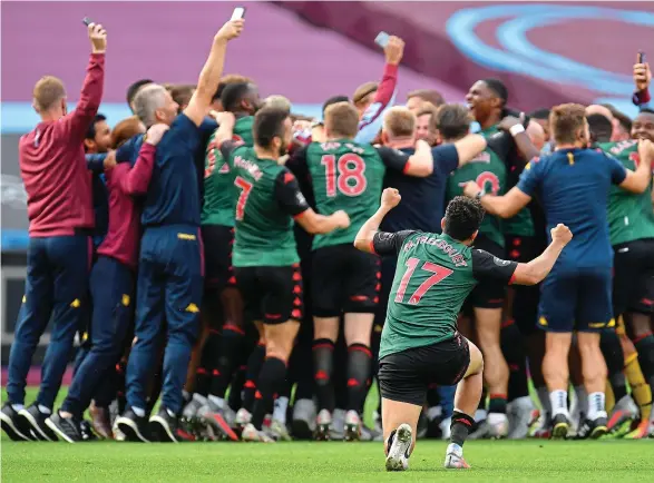  ??  ?? Heroes and Villans: the Aston Villa players and staff enjoy a post-match huddle. The celebratio­ns really began after they heard it was all over for Watford at the Emirates