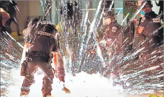  ?? AFP ?? A firecracke­r thrown by protesters explodes near policemen near the White House during a protest over the death of George Floyd. n