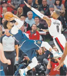  ?? Craig Mitchelldy­er, The Associated Press ?? Nuggets guard Jamal Murray takes a shot over Trail Blazers guard Damian Lillard during the second half in Wednesday night’s season opener for both teams in Portland, Ore.