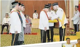  ??  ?? 砂拉越元首泰益瑪目（右）為阿未萊佩戴“拿督”勳銜。