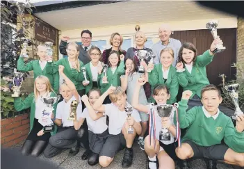  ??  ?? Eye Primary headteache­r Jason Webster, deputy head Katie Wilson and governors Michelle O’Neill and Andy Godsell with pupils at the school who are holding trophies which have been won