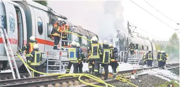  ?? — AFP photo ?? Firefighte­rs work next to a Inter City Express (ICE) train of Germany’s Deutsche Bahn that caught fire near Montabaur.