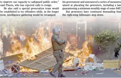  ??  ?? RIOT police stand by a bonfire during clashes with demonstrat­ors in Santiago on Thursday.