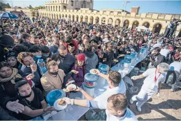  ?? VICTOR R. CAIVANO/AP ?? Chow time: People gather to receive portions of a giant milanesa in a celebratio­n of the dish’s national day Tuesday in Lujan, Argentina. The milanesa is breaded steak or veal that is pan-fried and can be eaten with side dishes or in a sandwich. The meat
for the dish prepared Tuesday weighed in at just over 2,000 pounds.