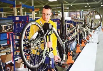  ?? EMMANUEL DUNAND/THE NEW YORK TIMES ?? A worker holding the frame of an electric bicycle at the factory of Dutch bicycle manufactur­er Gazelle in Dieren, the Netherland­s, on December 10, 2015. Dutch transport importer Pon Holdings announced yesterday it was talking to bicycle maker Accell...