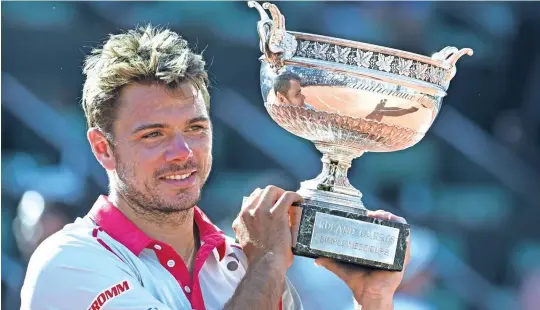  ??  ?? CUP OF CHEERS: Switzerlan­d’s Stanislas Wawrinka celebrates with the trophy following his victory over Serbia’s Novak Djokovic after the men’s singles final of the 2015 French Tennis Open at the Roland Garros in Paris.