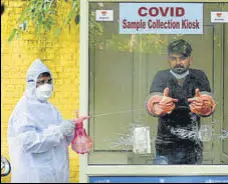  ?? PARVEEN KUMAR/HT ?? A health worker sanitises a sample collection kiosk during a testing drive in Gurugram on Wednesday