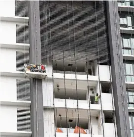  ??  ?? Risky job: Workmen on gondolas working on the facade of a skyscraper.