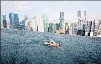  ?? PICTURE: REUTERS ?? A guest swims in the infinity pool of the Skypark that tops the Marina Bay Sands hotel towers in Singapore. Vancouver, Hong Kong and Singapore have all introduced higher taxes for foreign buyers in recent years.