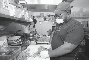  ?? JOHN MCCALL/SOUTH FLORIDA SUN SENTINEL ?? Prep cook Andrew Walker, hired in April with a $400 singing bonus at Bodega Taqueria y Tequila, chops cilantro in the kitchen of the Las Olas Mexican restaurant in Fort Lauderdale on Friday.